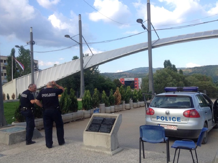 Ponte de Mitrovice com policiais poloneses, com a bandeira sérvia ao fundo | Foto por Sabrina Sasaki