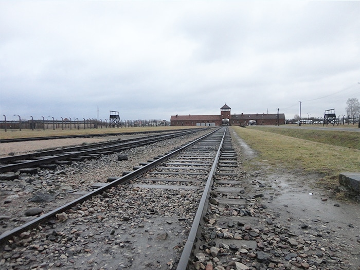 A entrada do Complexo Auschwitz – Birkenau e os trilhos de trem | Foto por Carolina Caio